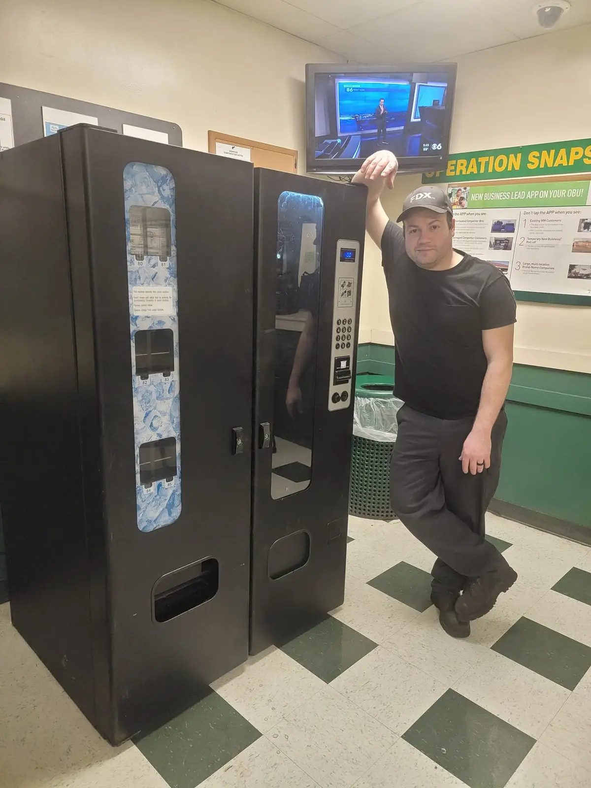 A vending operator standing beside a snack machine at a customer location